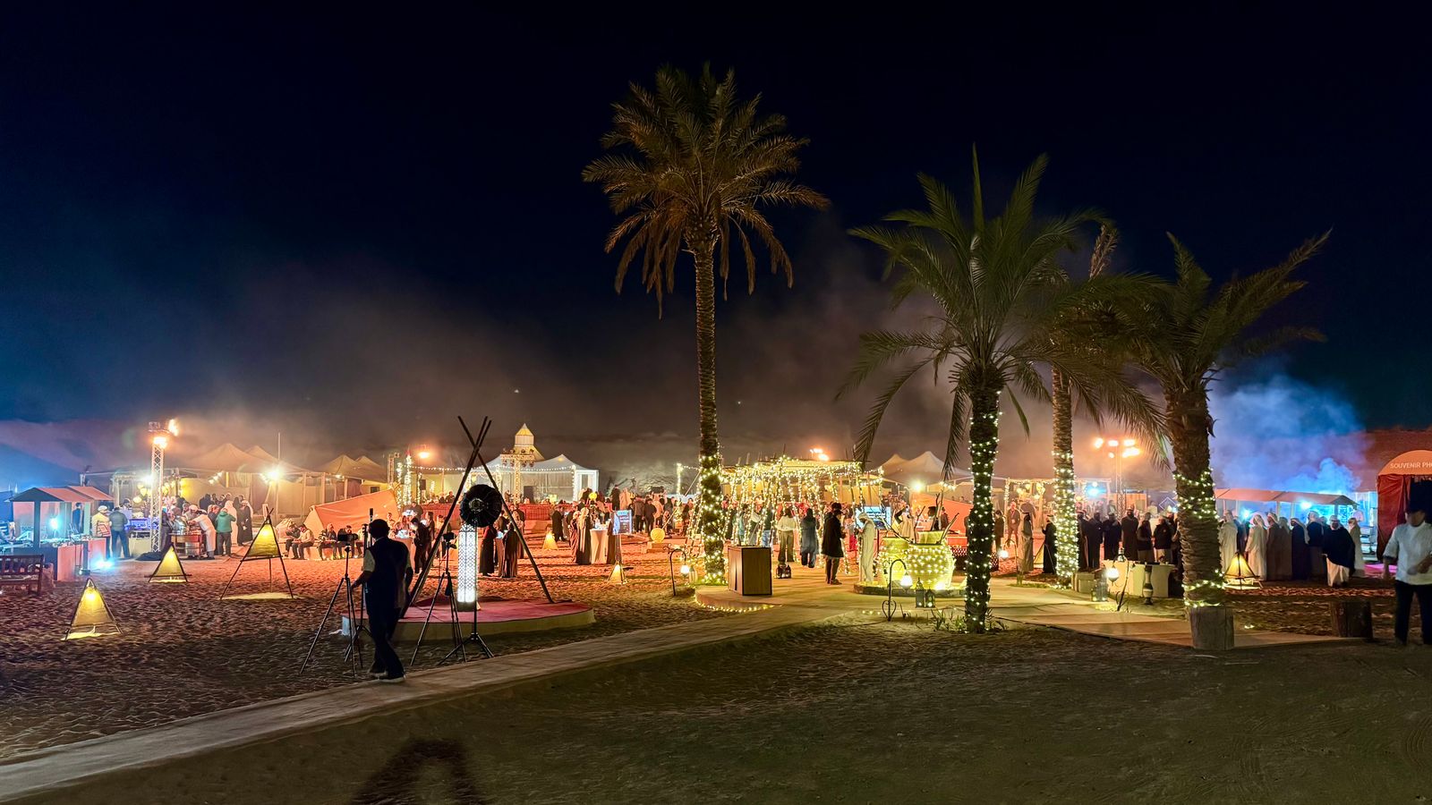 A night scene of deserts and palm trees with lights and food stalls