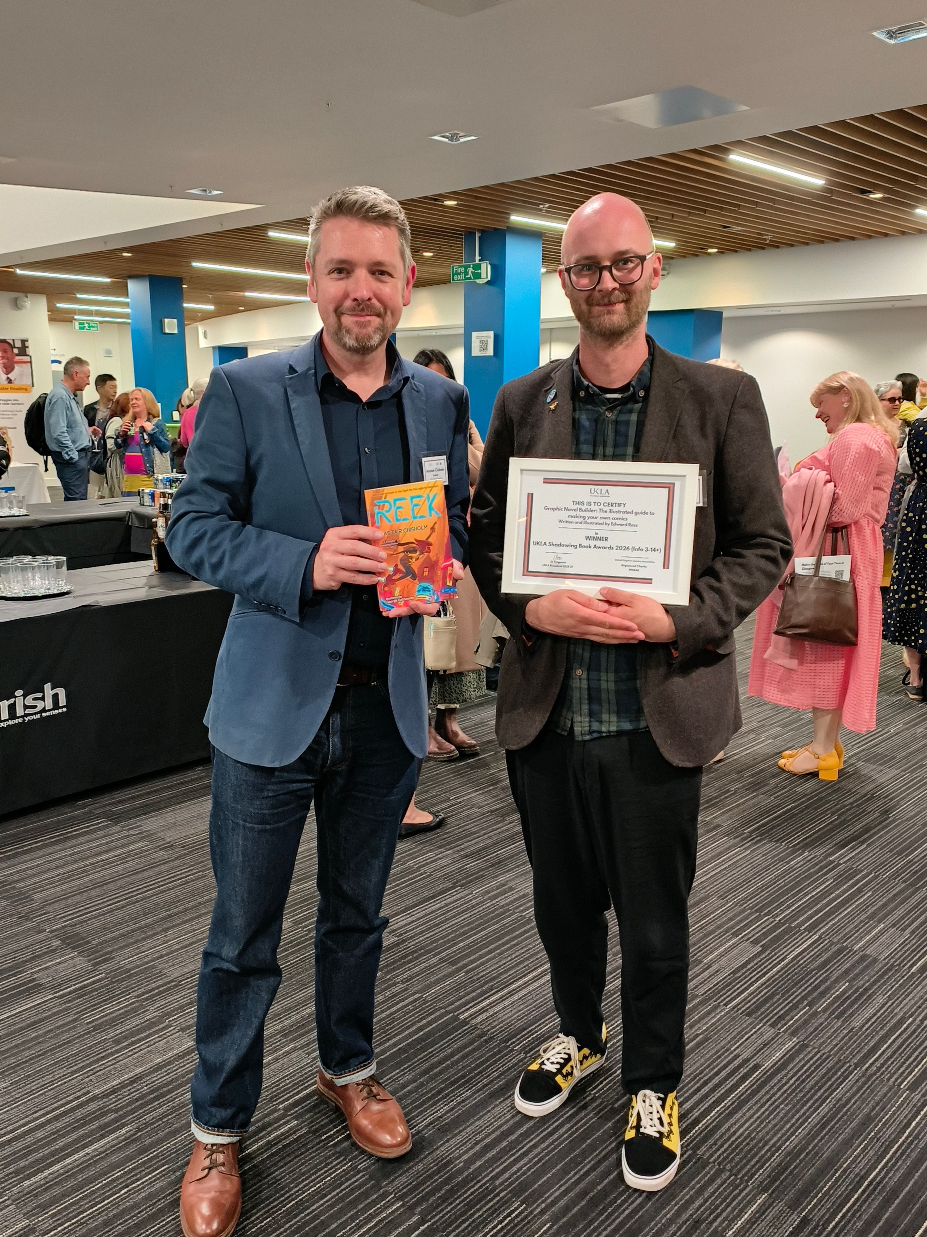 Alastair Chisholm and Edward Ross at the UKLA conference. Alastair is holding a copy of his book Reek, and Edward has his certificate as winner of the Info 3-14+ category Shadow Award for his book Graphic Novel Builder.